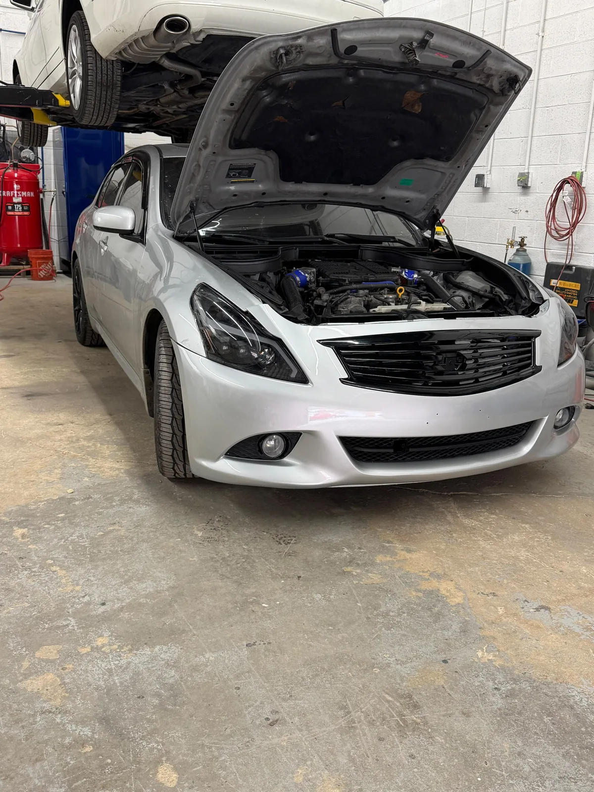 White sedan with hood open for service at Drive One